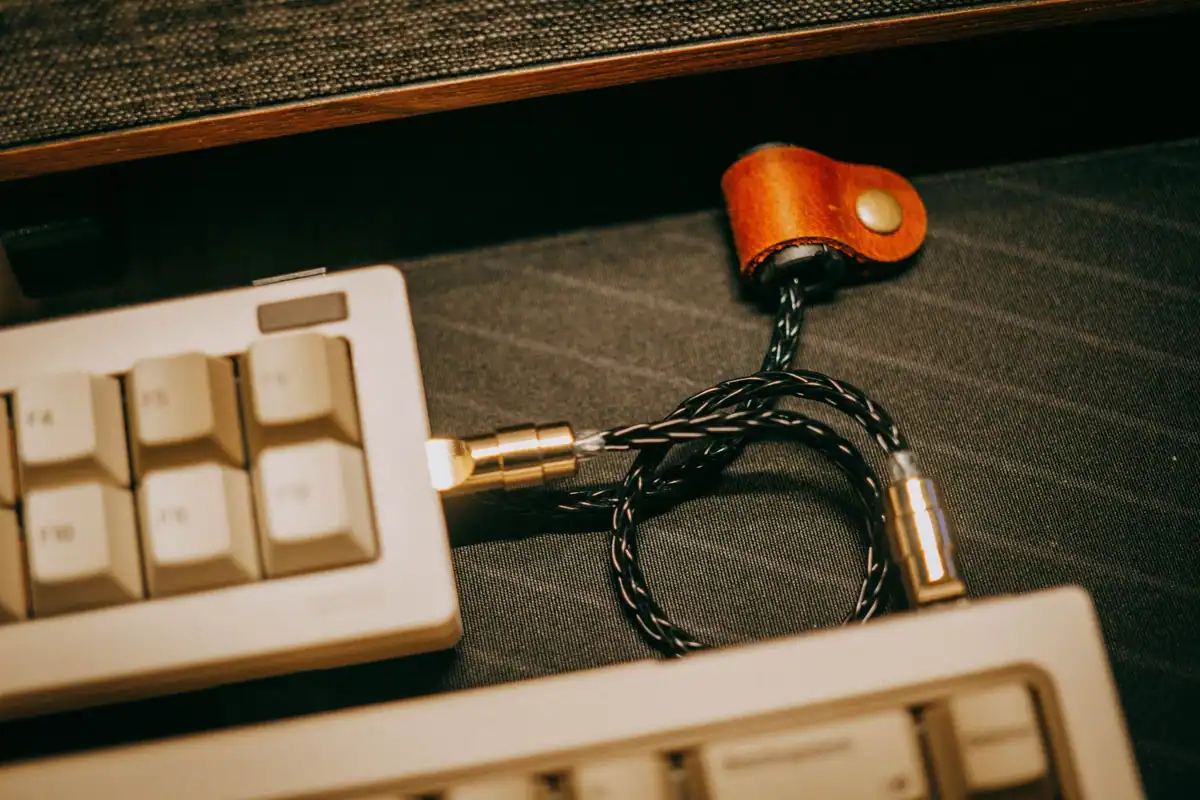 Cablu împletit cu mufă aurie, așezat pe o tastatură mecanică veche