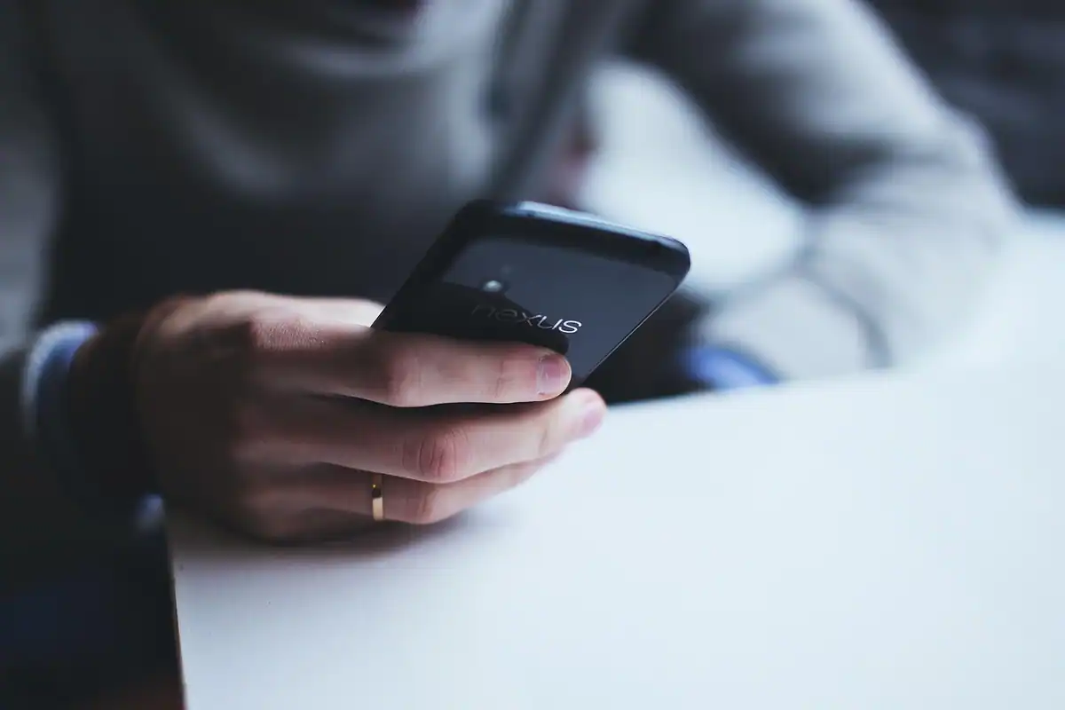 Baterie externă așezată lângă un smartphone pe masă, cu cablu de încărcare conectat
