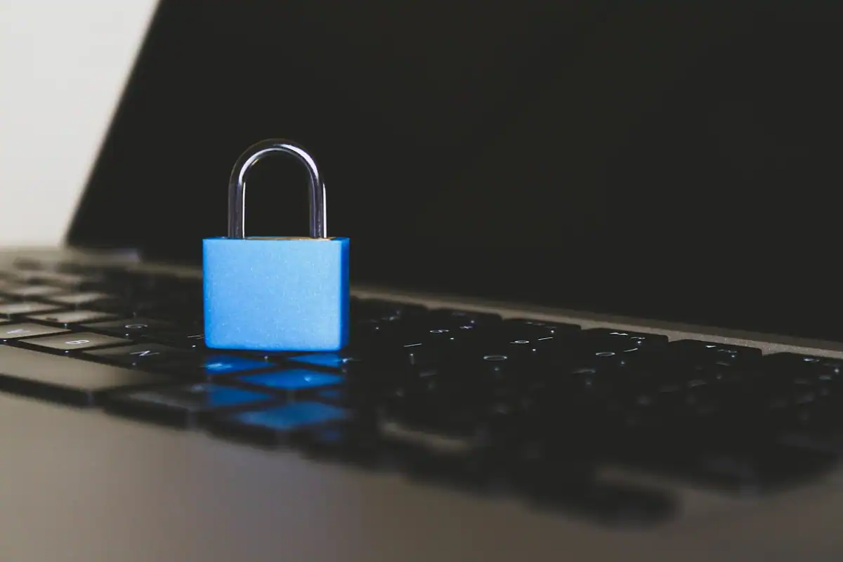 Lacăt albastru așezat pe tastatura unui laptop, simbol al protejării datelor personale