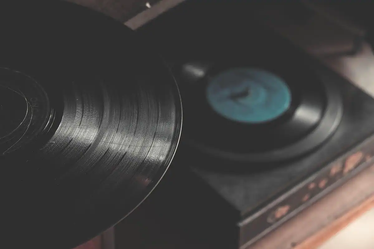 Pickup cu disc de vinil așezat pe un raft, în fața unei instalații audio de acasă