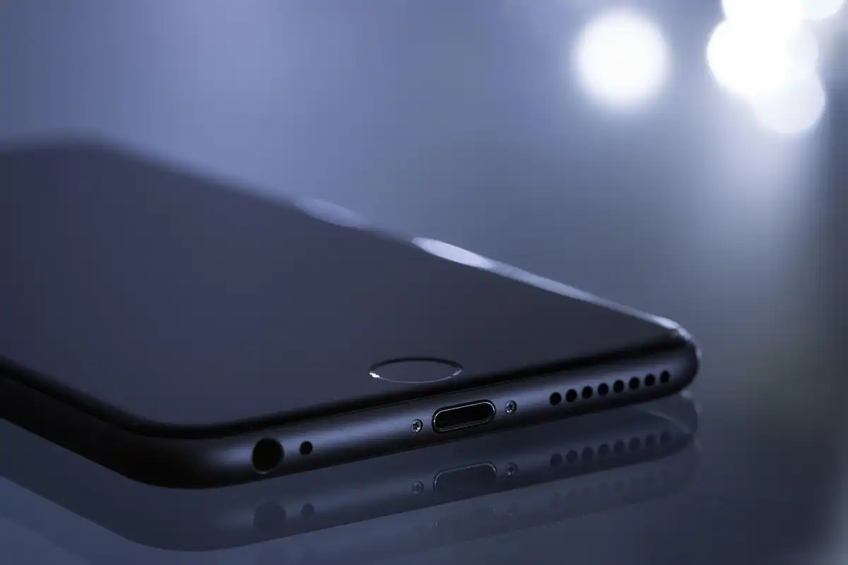 Telefon aflat la încărcare pe un birou din lemn, cu cablul conectat în portul de jos