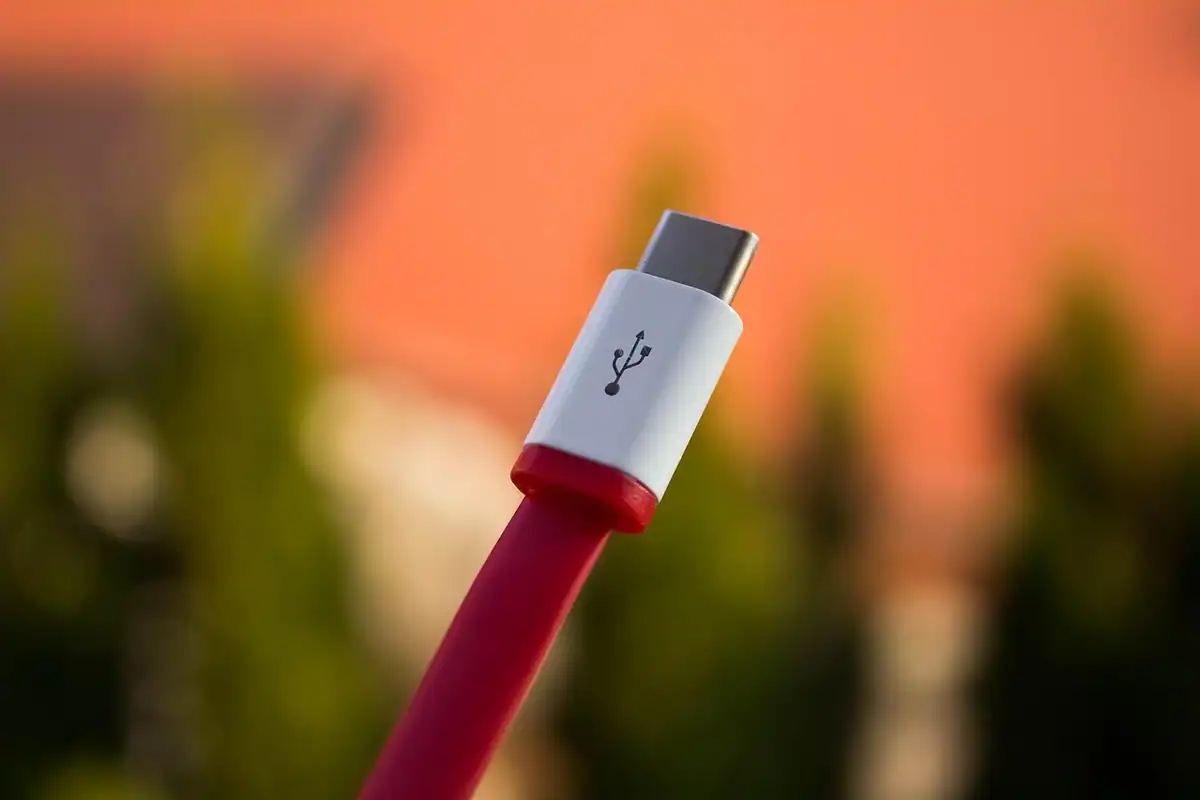 Mufă USB-C albă cu roșu, văzută de aproape, pe un fundal portocaliu neclar