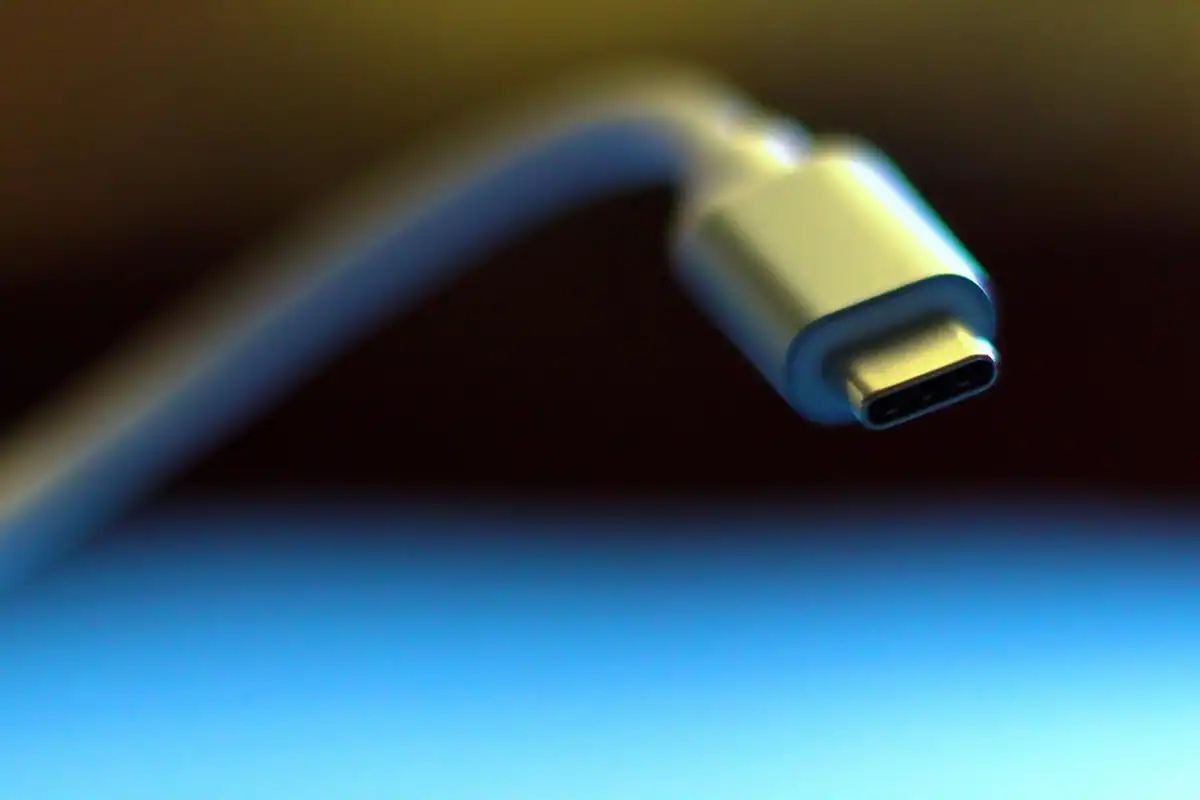 Capătul unui cablu USB-C, fotografiat din apropiere, cu fundal albastru estompat