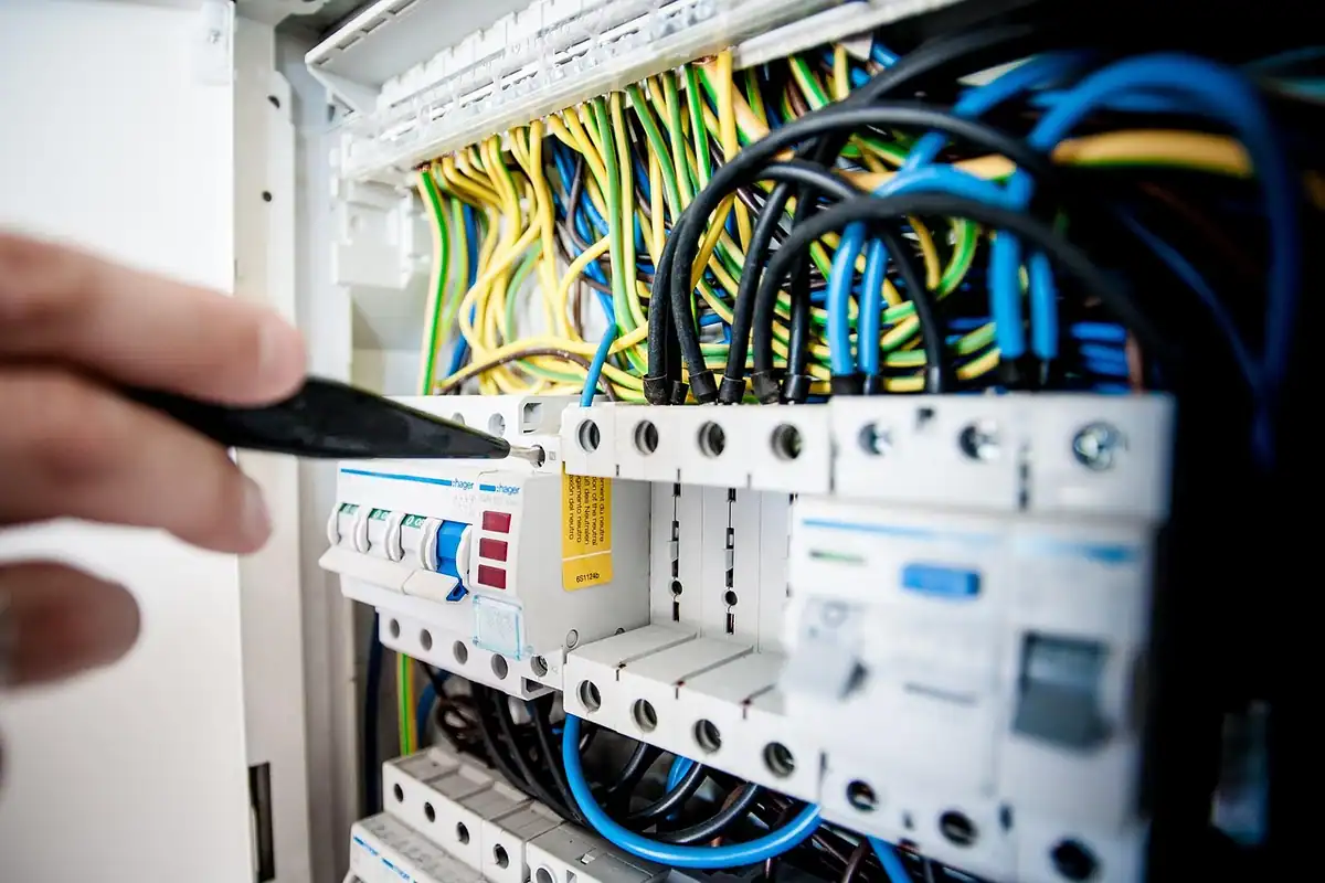 Mâinile unui electrician care conectează firele într-o doză de montaj a întrerupătorului