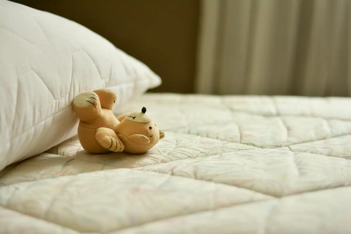 Cablu de încărcare lăsat pe pernă într-un pat, lângă telefonul pus la încărcat