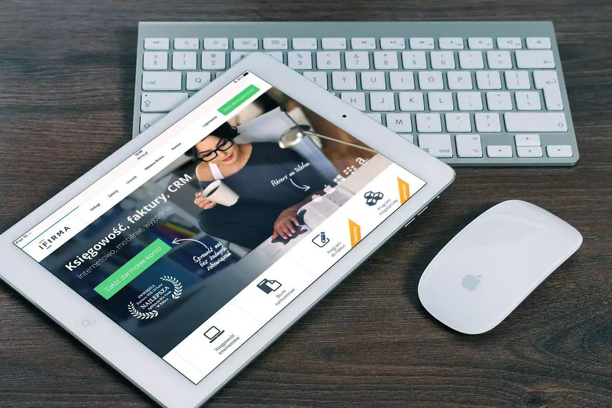 Mouse wireless așezat pe un covoraș de birou, lângă laptop, într-un spațiu de lucru