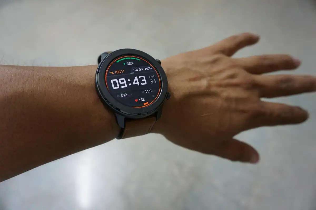 Mână cu un smartwatch negru, care afișează ora și mai multe date de activitate