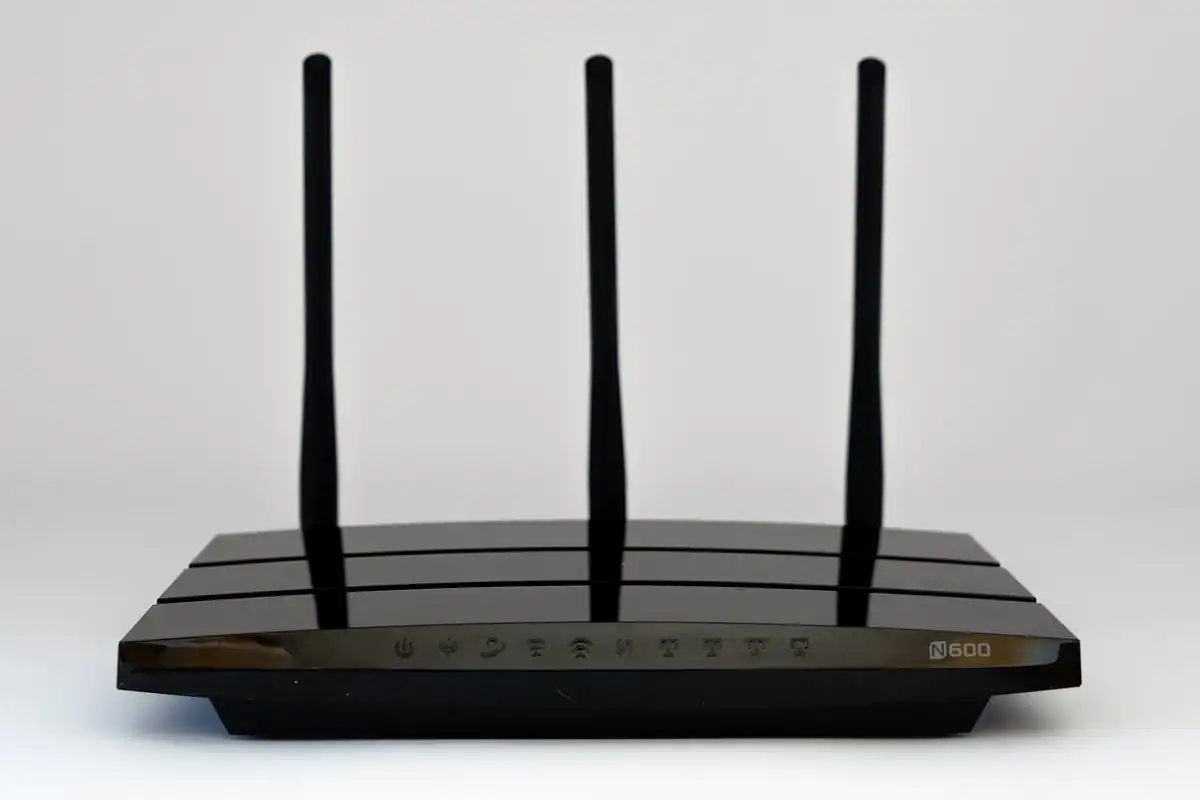 Router negru cu trei antene, așezat pe un fundal alb