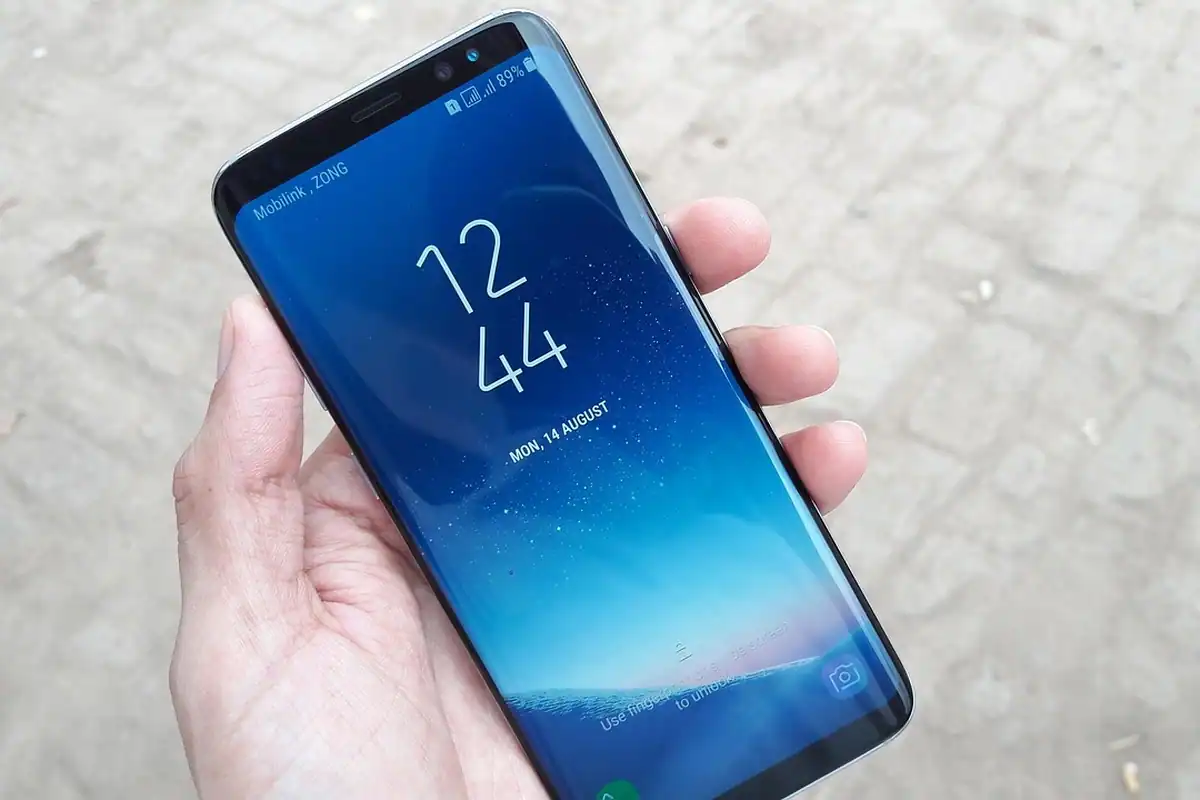 Mână care ține un smartphone cu ecranul de blocare afișat, pentru protejarea accesului