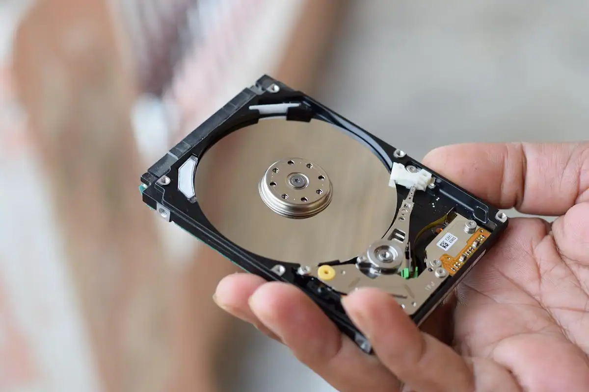 SSD extern portabil așezat pe un birou, lângă laptop, cu carcasă metalică compactă