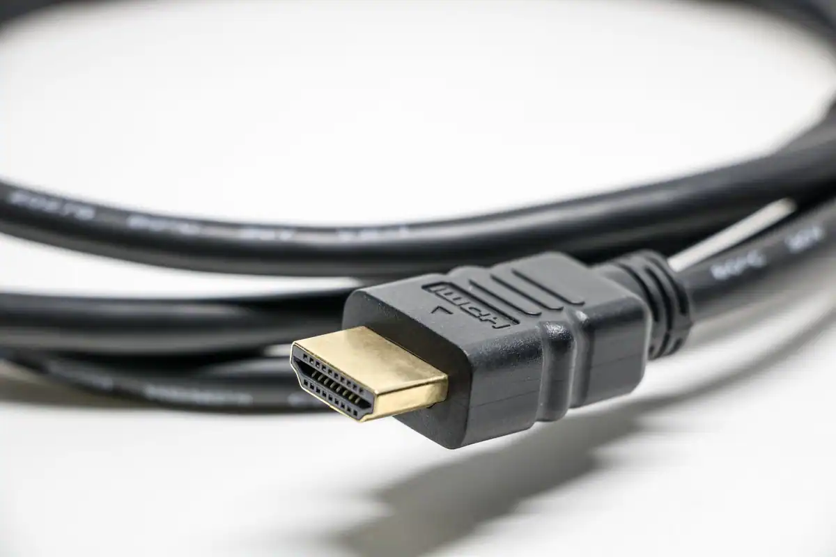 Cablu HDMI negru cu mufă aurie, văzut de aproape pe un fundal alb