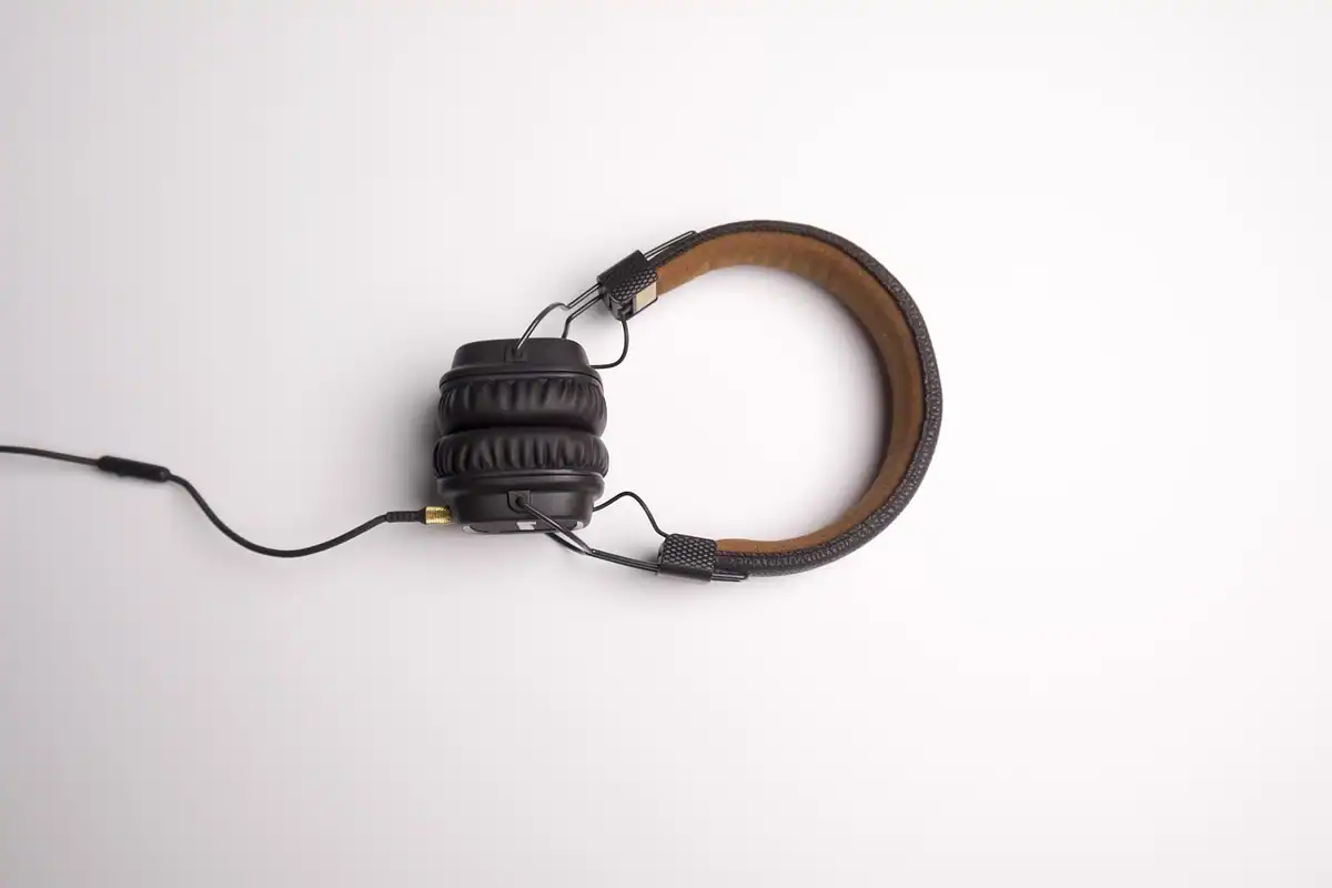 Căști over-ear cu cablu și bandă maro, așezate pe un fundal alb